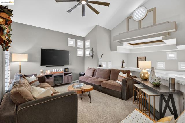 Carpeted living room with high vaulted ceiling and a ceiling fan