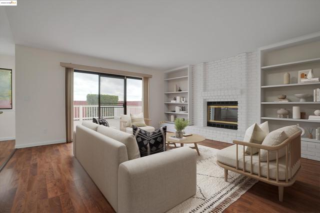 Living area with a brick fireplace, wood finished floors, and built in shelves