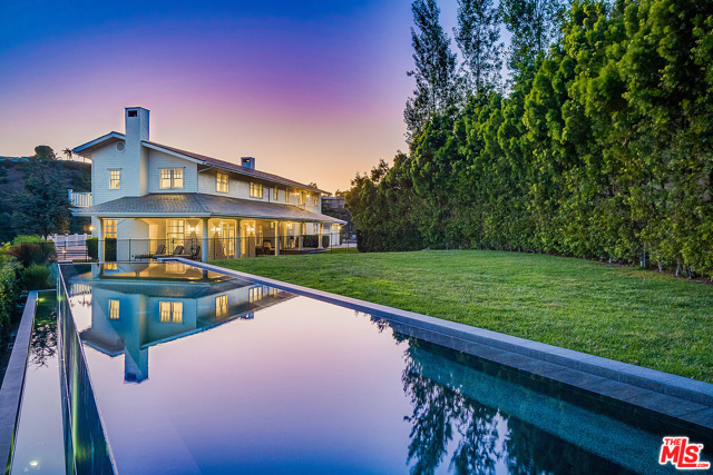 1145 STRADELLA Road Los Angeles, California NEW PRICE & VACANT OCTOBER 1ST! Gated and private, this stunning East Coast Traditional is sited at the end of a long driveway on over an acre of park-like grounds featuring a salt water infinity pool, grassy lawn area and large motor court allowing for ample parking. The covered front porch wraps around to an enormous patio deck overlooking panoramic canyon and city views. Extensively remodeled in 2011 and exquisitely furnished, this fabulous residence features 5 bedrooms and 5.5 baths. Impressive Primary suite w/ two balconies, high ceilings, spa-like bath and dual walk-in closets; plus 3 additional en suite bedrooms upstairs and a guest/maid's room downstairs. Large scale public rooms, fireplaces in both Living and Dining rooms, paneled library and chef's kitchen w/ center island, top of the line appliances and office nook- laundry room with 2 washers & 2 dryers. Other features include a wine tasting room and state of the art screening room complete this very special offering.