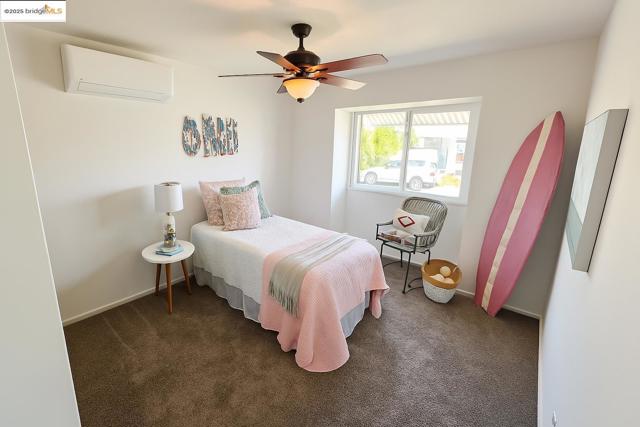 Bedroom with carpet, a wall mounted AC, and a ceiling fan