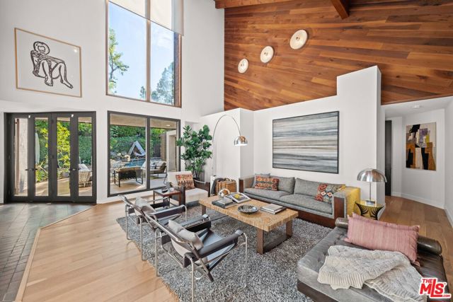 1051 Angelo Drive Beverly Hills, California Nestled in prime BHPO and surrounded by $100 million properties, stands an extraordinary architectural home. With its voluminous interiors and private indoor-outdoor entertaining spaces, this residence effortlessly combines the timeless beauty of wood and the transparency of glass, providing an exquisite backdrop for the display of contemporary art. This remarkable property offers a harmonious fusion of luxury and artistic expression, situated in a highly sought-after location. The interiors have been refreshed while maintaining the integrity of the unique architectural style. The one of a kind asymmetric high volume roof line and sunk in entertaining space offers a great room perfect for entertaining. It opens up directly to a newly renovated and private backyard featuring pool and spa. Its proximity to the prestigious neighborhoods of Holmby Hills and Beverly Hills further enhances its allure, making it a coveted haven that seamlessly blends elegance and sophistication.