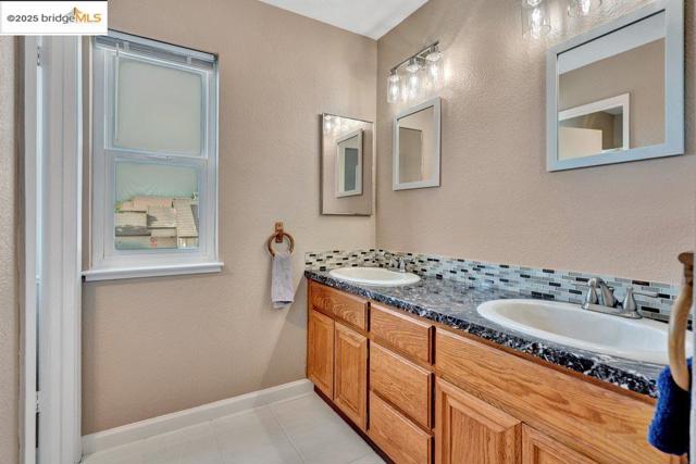 Full bathroom with a textured wall, double vanity, tasteful backsplash, and tile patterned floors