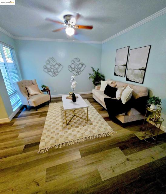 Living area featuring ornamental molding, a textured ceiling, and wood finished floors