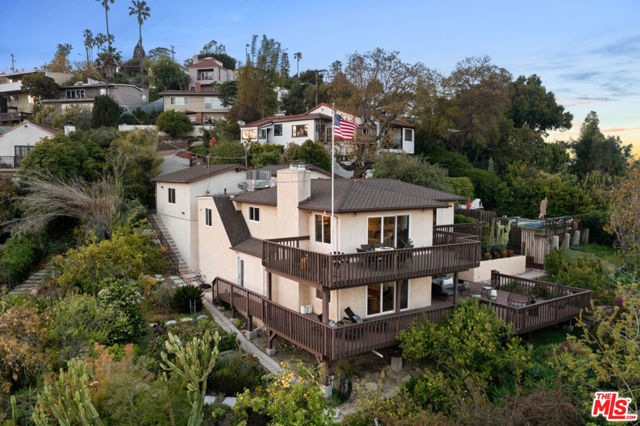 A very rare find in the Franklin Hills neighborhood of Los Feliz. This 3-bedroom, 2-bathroom home with 2047 square feet of living space is situated on 4 lushly landscaped lots amassing 18,898 square feet, offering privacy and sweeping city views. Set back from the street and down a long driveway sits this serine retreat which was originally built in the 1950's and remodeled throughout the years. The front entry patio with a bubbling fountain sets the tone.  Past the entry gate you will be welcomed by an open atrium with vaulted wood ceilings and skylights. The home is warm and inviting with an open and casual floorplan and a nice indoor/outdoor flow. The spacious south-east facing living room is filled with natural light and is anchored by a marble fireplace and features plank flooring, crown moldings, recessed lighting and a sliding glass door that opens to a wide view deck, perfect for al fresco dining and unwinding from the day. Off the dining room is a cooks' kitchen with a Viking range, microwave, granite countertops with a breakfast bar, abundant custom cabinetry, and a Fisher & Paykel dishwasher.  A large bedroom with glass doors and a remodeled bath with Travertine marble, double sinks, and large shower with a built-in seating area and a seamless glass door complete this level. The lower level includes a lounge area with a wet bar and wood floors, an oversized primary bedroom with fireplace and two sliding glass doors that open to a massive redwood deck, and a guest bedroom with custom closets, plus a bath. The professionally landscaped parklike backyard is one of a kind with meandering stone pathways, numerous fruit trees, a vegetable gardening area and gorgeous flora and fauna, plus room to build a pool & spa, or ADU/guest house (check with your contractor).  Additional features include a 2-car garage, dual paned windows and doors, central air and heat, laundry room, and a large storage shed.  Franklin Elementary school district.  This is an amazing opportunity to create your own private compound!  All lots are zoned LAR-1.