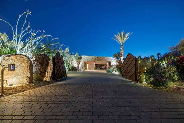 Stunning Guy Drier architectural masterpiece in the heart of Rancho Mirage. This 10,019 SF, privately gated compound is situated on 2 acres, and features the finest in indoor/outdoor living. The main house has a expansive primary wing, with two luxurious master baths,, washer and dryer and generous walk-in closets and an executive office. There are also three guest suites, with access to the backyard. There is also a next level self-contained guest house that features a formal living room, full kitchen + catering kitchen, laundry room, guest suite, gym and a huge covered  patio. Amenities also include a resort worthy pool/entertaining area, championship tennis court with pavilion, bocce ball court and a putting green. This property also features Smart home automation, state of the art security system with cameras, and extensive solar system. Offere furnished per inventory