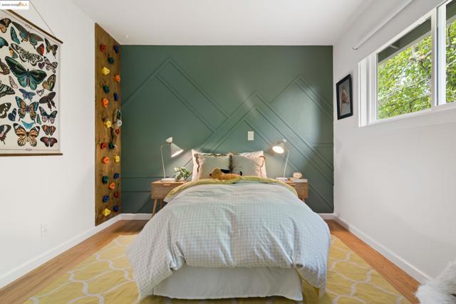 Bedroom with wood finished floors and an accent wall