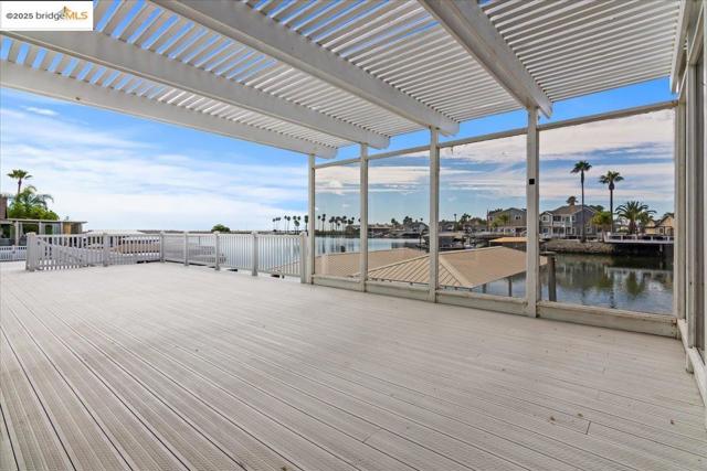 Wooden deck featuring a water view, a pergola, and a residential view