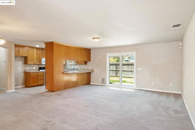 Kitchen featuring open floor plan, brown cabinetry, light colored carpet, and stove