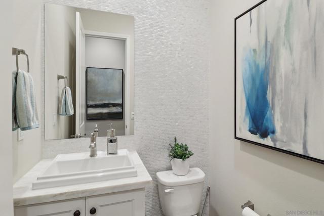 The powder room is gorgeous with mosaic type tiles adorning the entire back wall. This feature is rich and stylish. Sure to impress your guest.