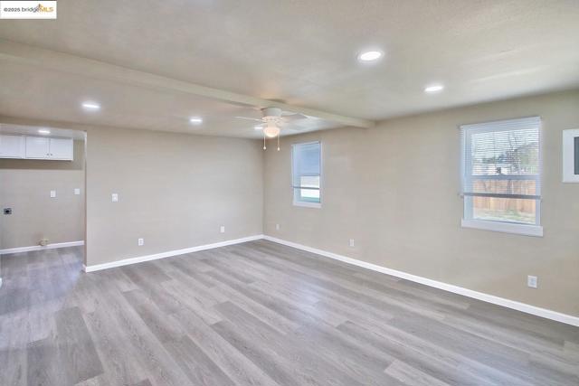 Empty room featuring beamed ceiling, light wood-style floors, recessed lighting, and a ceiling fan