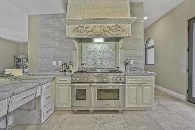 Gorgeous Wolf gas range with griddle and grill and designer precast stone hood , as well as a nice domestic office workspace