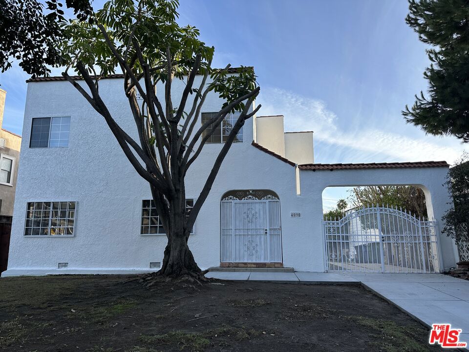 Ideally located near Larchmont Village, Hancock Park, and Koreatown, this beautifully updated Spanish-style home sits on a spacious lot in the historic Wilshire Park neighborhood. Featuring a gated driveway, the home welcomes you into a foyer with a grand wood staircase.  The light-filled living room with fireplace and ceiling fan flows into a large dining room, which opens to a modern kitchen with granite counters and new stainless steel appliances. Sliding doors lead to a covered patio and convenient laundry room with washer and dryer. A small bedroom and bathroom off the kitchen make for a perfect office or guest room.  Upstairs, there are two spacious bedrooms with walk-in closets, a stylish bathroom, and a generous primary suite with an en-suite shower. The detached garage and long driveway offer ample parking and storage. With a great walk score and easy freeway access, this home combines comfort, style, and convenience.