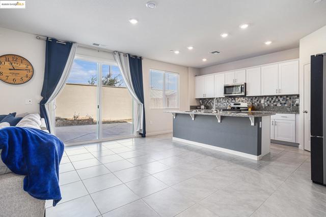 Kitchen featuring a breakfast bar, dark stone counters, decorative backsplash, white cabinetry, and appliances with stainless steel finishes