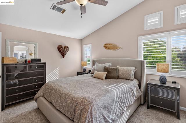 Bedroom with lofted ceiling, carpet, multiple windows, and ceiling fan