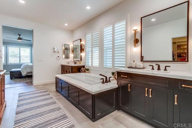 with dual custom vanities, soaking tub, shower and walk-in closet