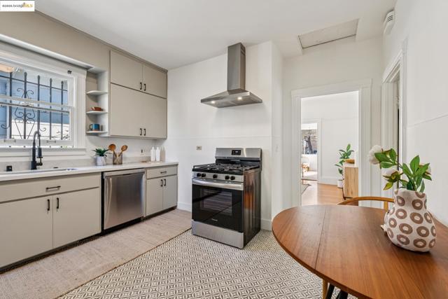 Kitchen with stainless steel appliances, open shelves, wall chimney exhaust hood, and gray cabinetry