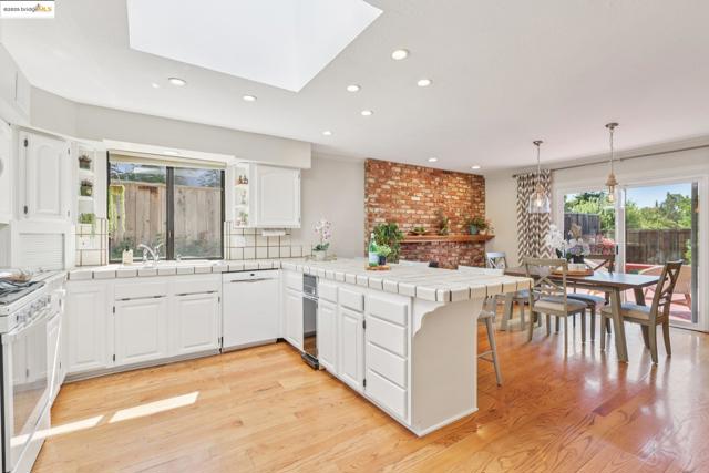 Kitchen with a peninsula, light wood-style flooring, white appliances, white cabinetry, and recessed lighting