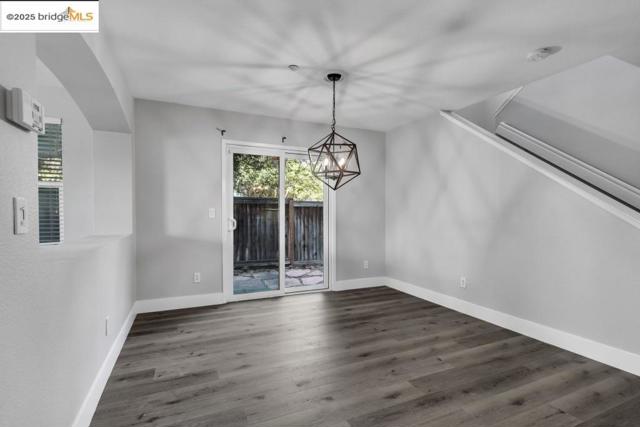 Unfurnished dining area featuring dark wood-style flooring and a chandelier