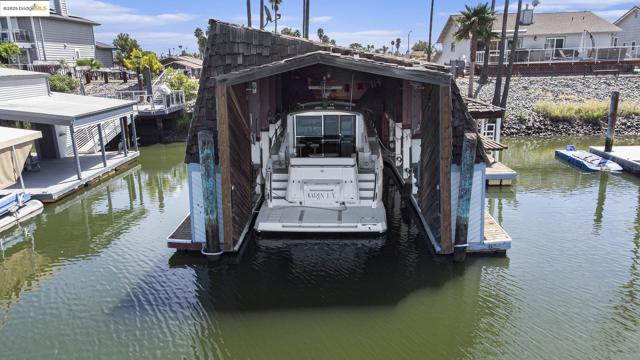 Dock area with a water view, boat lift, and a residential view