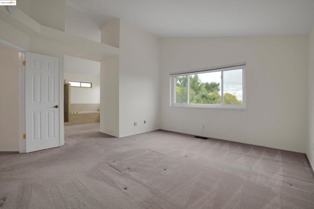 Unfurnished room featuring light colored carpet and high vaulted ceiling