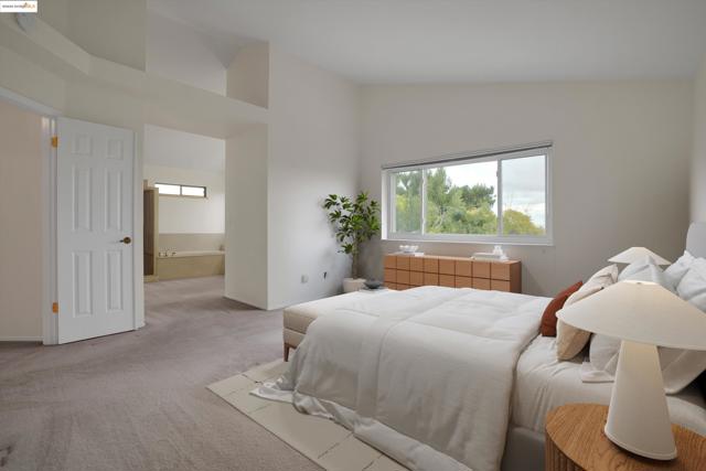 Carpeted bedroom with high vaulted ceiling and ensuite bath