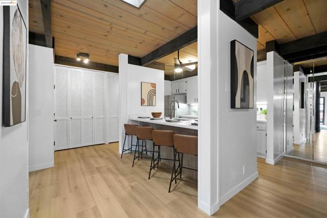Kitchen featuring a kitchen bar, a wood ceiling with exposed beams, light countertops, light wood finished floors, and white cabinets