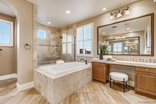 Luxurious dual primary baths with separate spaces. One side features a walk-in shower, vanity, water closet, and walk-in closet. The other offers a large vanity, oversized shower, soaking tub, makeup vanity, water closet, and expansive walk-in closet.