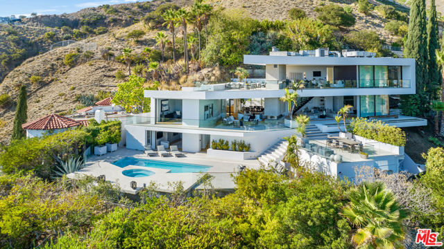 7869 Fareholm Drive Los Angeles, California Featured on the cover of Architectural Digest and winner of AIA Best Residential Design, this stunning home soars over the city lights with breathtaking views spanning from downtown Los Angeles to the Pacific Ocean. Floor-to-ceiling automatic glass doors slide open to seamlessly blend indoors and out. A spacious yard and wide decks surround the home offering numerous options for outdoor seating, dining and entertaining. Bask in the sun on the expansive pool deck or the upper outdoor patio. The floating concrete staircase leads up to a jaw-dropping primary suite with 2 fireplaces and a luxurious bath. Gated and private, this was also the former home of fashion designer, Randolph Duke. One of the most easily accessible homes in the hills with panoramic views, privacy and outdoor space.