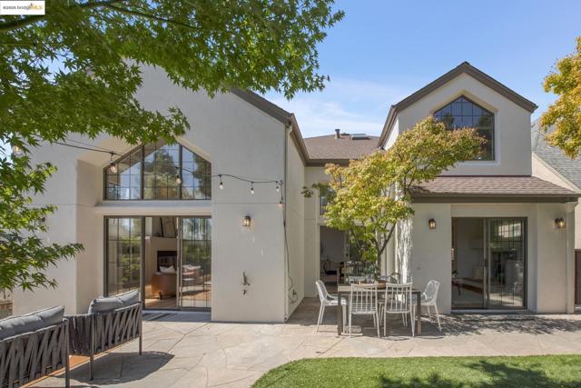 Rear view of property featuring roof with shingles, a patio, and stucco siding