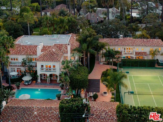 812 N Bedford Drive Beverly Hills, California Extraordinary opportunity to acquire a rare double lot compound in the coveted Beverly Hills flats. Offering just under one acre flat, 812 N Bedford Drive is one of the largest estates in the area, encompassing two parcels and ample amenities. The extravagant offering includes an incredible six-bedroom main home, a five-bedroom guest home, three additional half-bathrooms, a tennis court, a pool and a nine-car garage. The Spanish-style oasis warmly greets guests with an elegant motor court, a tile roof, towering palms and verdant landscaping. Inside, find a dramatic double-height entry, coffered ceilings and an all-hardwood kitchen with marble slabs and stone. Enjoy an elegant office that looks out to the tennis courts and a beautiful primary suite with an outdoor patio, a sitting area and a fireplace. There's no shortage of space to live, work and luxuriate within these walls. Outside is a paradise, presenting recreation and relaxation at your doorstep-swim in the pool, cook and dine al fresco, and play on the tennis courts, all surrounded by lush greenery. Square footage as listed includes the main house at approximately 9288 sf and the 5-bedroom guest house at 4000 sf.