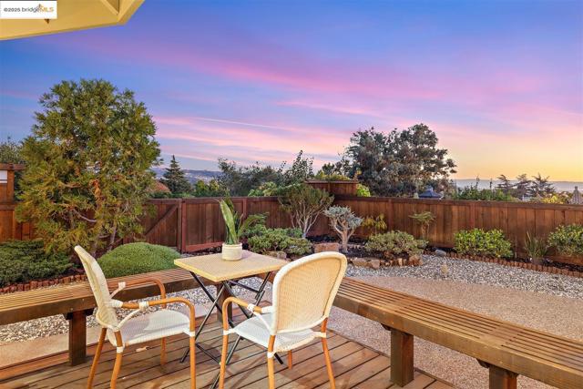 Deck at dusk with outdoor dining area and a fenced backyard