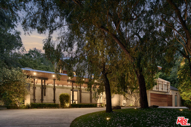 7728 Woodrow Wilson Drive Los Angeles, California Conceived by LA architect Jeffrey Mills in 1997, the structure was a response to the surrounding environment, including light and landscape, as well as the clients' refined aesthetic as art collectors. Today, when many contemporary architectural designs prioritize large white boxes and overlook the importance of gardens and landscapes, this property stands out for its ability to retain and masterfully integrate the raw beauty of nature. Architecture Verdure is a term coined to describe a specific architectural style that blends modernist and contemporary principles with a strong integration of nature. The house designed in this style incorporates elements of both modern architecture and the surrounding natural environment to create a unique aesthetic experience. The design features panoramic glass, which allows for expansive views of the surrounding nature, while solid wood beams with textures reminiscent of tree bark add a tactile and organic feel to the space. Every area of the house is designed to connect dynamically with its surroundings, creating a sculptural experience. In addition to the use of natural materials, the house celebrates the art of human engineering through exposed hardware and steel elements. The plaster work in organic tones seamlessly merges with the landscape, further enhancing the connection between the built environment and nature. It signifies the style's emphasis on integrating nature's textures and resonance as core elements of the design, while still adhering to modernist and contemporary architectural principles. The concept of bridging the indoors and outdoors has been a recurring theme in modernist architecture since its inception in the mid-twentieth century. Influenced by iconic homes such as Rudolph Schindler's Kings Road House, Villa Verdure draws on the legacy of modernism while bringing it into a contemporary world that seeks a deeper connection with nature. The style takes inspiration from various sources, including the Japanese practice of "forest bathing," which emphasizes the healing and restorative power of immersing oneself in nature. Recent research on the positive effects of birdsong on the human brain and consciousness also informs the design approach. The aim is to create spaces that enhance human experiences, promote health, and stimulate growth and creativity. In summary, Architecture Verdure represents an architectural style that crafts a deep connection with nature while expressing the relevance of contemporary culture and spatial aesthetics. It seamlessly integrates natural elements, materials, and textures into the design, resulting in a total aesthetic experience where nature meets culture at every crafted moment.