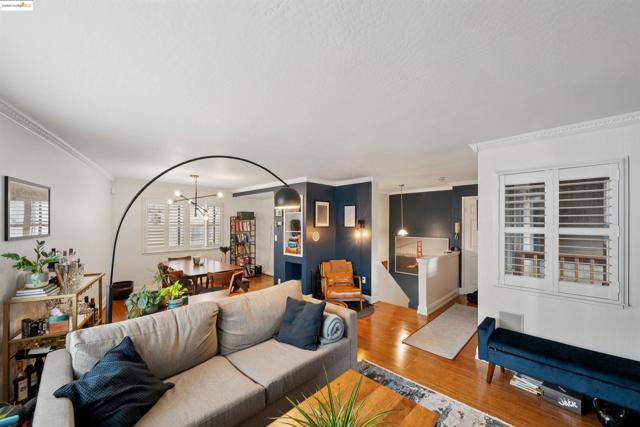 Living room featuring wood finished floors, ornamental molding, and a chandelier