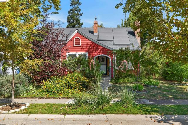 Classic New England architecture with wooden ship-lap siding, arched entry, mature pollinator-habitat English garden.