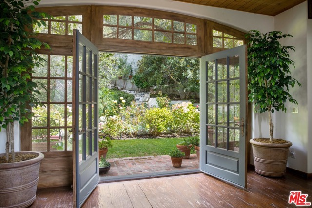 9989 Liebe Drive Beverly Hills, California French Country Farmhouse in heart of private Benedict Canyon paradise on quiet acreage and cul-de-sac. Rarely found these days, the residence provides immense volume in most rooms with soaring ceilings lifted by hewn timbers and warmed by richly distressed hardwood floors. Raised above street level and gated, guests enter secret Front Garden and then are transported to entertaining rooms of generous proportions -- all overlooking green lawn & flower beds surrounding a waterfall Lagoon Pool. Walk trail to full scale Tennis Court, lit at night and offering not only games, but opportunity for further entertaining or other sports, Basketball anyone? One feels like you may be in Sun Valley or Mammoth Lakes ready to enjoy a ski vacation while resting in tranquility far from the madding crowd only a few minutes away in Beverly Hills or Sunset Strip. Unforgettable Kitchen, spacious bedroom suites, the comforts are endless. Move in or create your own design palate. Uniquely special.
