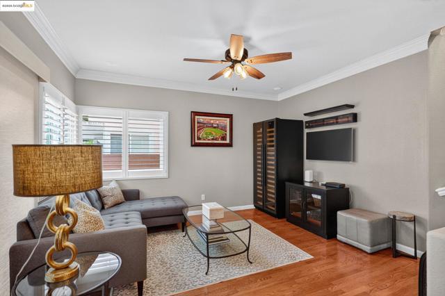 Living area with wood finished floors, crown molding, and a ceiling fan