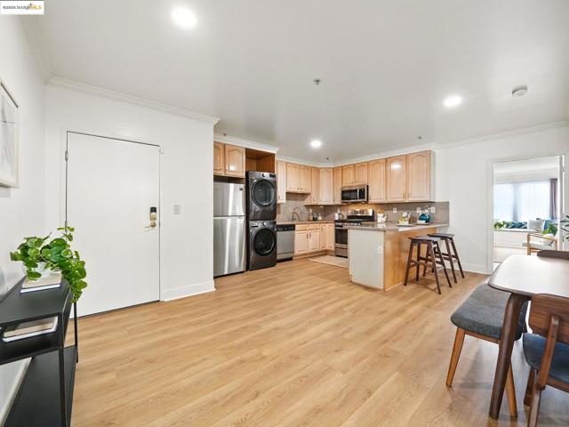 Kitchen with estacked washer and dryer, crown molding, a peninsula, light brown cabinets, and light wood finished floors