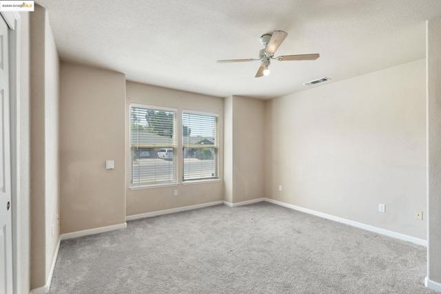Spare room with light carpet, a textured ceiling, and ceiling fan