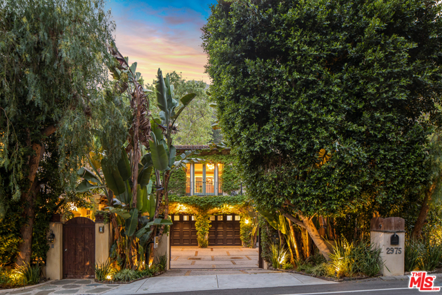 2975 Mandeville Canyon Road Los Angeles, California Luxurious Brentwood hideaway is your escape to the Mediterranean in this stunning resort-inspired abode. Set behind a secure gated entry that flows into a gallery space with double-height ceilings, large windows, and an abundance of natural light that creates an ethereal feel. The vine-covered exterior paired with a clay tile roof, sun-soaked terraces, and an open-plan layout exudes timeless elegance. An abundance of living space on offer, including a formal dining room under a beamed ceiling, a family room w/a fireplace, playroom by the kitchen, and a sunny breakfast nook with French doors to the deck. Each bedroom is impeccable with the main suite enjoying a large walk-in closet, a beautiful fireplace, a luxe ensuite bath, and French doors that open out to garden views. A serene pool with a waterfall, spa, and Tiki bar awaits in the lush grounds, along with sycamore trees and fruit trees dotted throughout the gardens. A separate guest studio offers luxurious accommodation for lucky friends. There's garages for four-cars, wood walkways throughout the gardens, dual offices for those who work from home, incredible views, and so much more to discover. Bespoke and unique, this home is an example of intricate detailing done so well, its a treat for the senses.