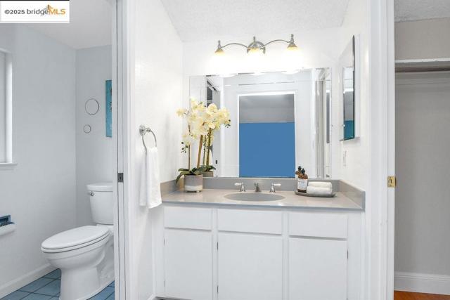 Bathroom with vanity, light tile patterned flooring, and a textured ceiling