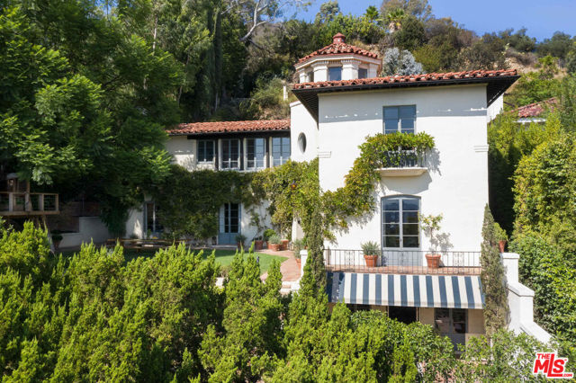7475 Hillside Avenue Los Angeles, California Perched atop a private lot in the foothills of Hollywood, on a discreet cul-de-sac, this expansive 1920s Spanish estate offers unparalleled views, brilliant design, and incredible original details. Originally built in 1926, yet meticulously updated by design firm Pierce & Ward, this 7 bedroom, 5.5 bathroom estate, including a guest apartment, offers lush grounds, a sparkling pool, tiled courtyards and a perfect floor plan. A private, secure entrance leads past tiered gardens, which include espaliered citrus specimens, organic vegetable boxes, and other spectacular plantings. A large flat, grassy pad leads to a dramatic entrance foyer, with original inlaid wood floors and a stenciled ceiling that sets the tone for the magic that follows. The formal living room features a hand-painted stone fireplace surround, beautiful built-ins, and French doors that lead to large outdoor spaces. The dining room, brimming with natural light, also has French doors leading back to the grassy front lawn, offering majestic city views. Connected to the dining room is a perfectly outfitted and updated chefs kitchen with a built-in breakfast nook. The kitchen connects to an office/family room also with French doors opening to the expansive outdoor patio. A guest room with a bathroom plus a powder room completes the first floor. Upstairs are four bedrooms, two of which open to the pool. The primary suite offers jaw dropping downtown and city views, incredibly appointed closets, and windows that look out onto the sunny grounds below. From the pool level, meander up secret garden steps to a level of the property that offers even more explosive views, a tub for ice bath soaks, an outdoor shower, and a barrel sauna. Above the two-car garage, equipped with electric charging ports, find the spacious guest apartment, with a kitchenette, bathroom and its own terrace. Special and rare, you will never want to leave home.