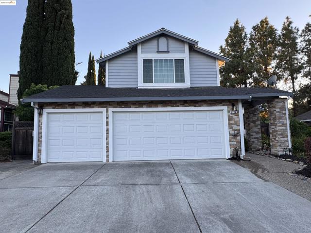 View of front of house featuring concrete driveway, a shingled roof, stone siding, and a garage