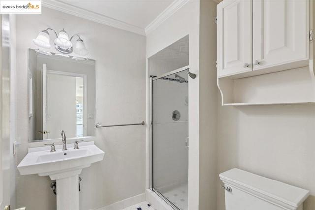 Full bathroom featuring a shower stall and ornamental molding