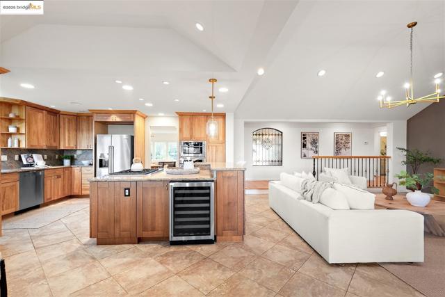 Kitchen featuring lofted ceiling, hanging light fixtures, beverage cooler, backsplash, and a kitchen island