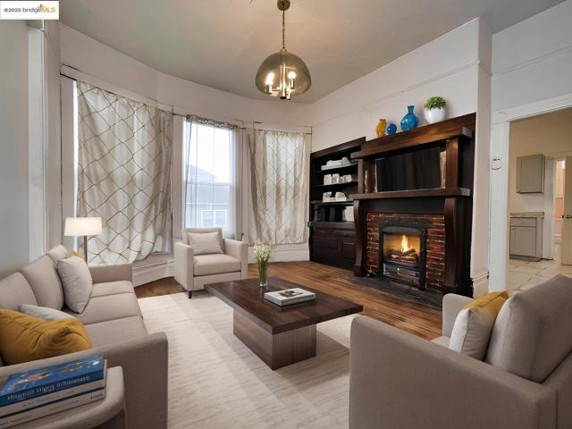 Living room with a fireplace with flush hearth, light wood-style flooring, and a chandelier. Virtually staged.