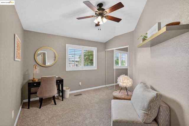 Carpeted bedroom featuring vaulted ceiling, a textured wall, and ceiling fan
