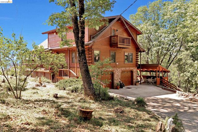 View of property exterior featuring stone siding, an attached garage, driveway, and a balcony