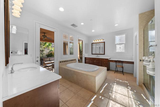 Primary suite spa bathroom with double sinks, oversized bath tub, walk in shower, and two walk in closets. two doors leading out to covered outdoor patio overlooking the gorgeous back yard and pool with mountain views.