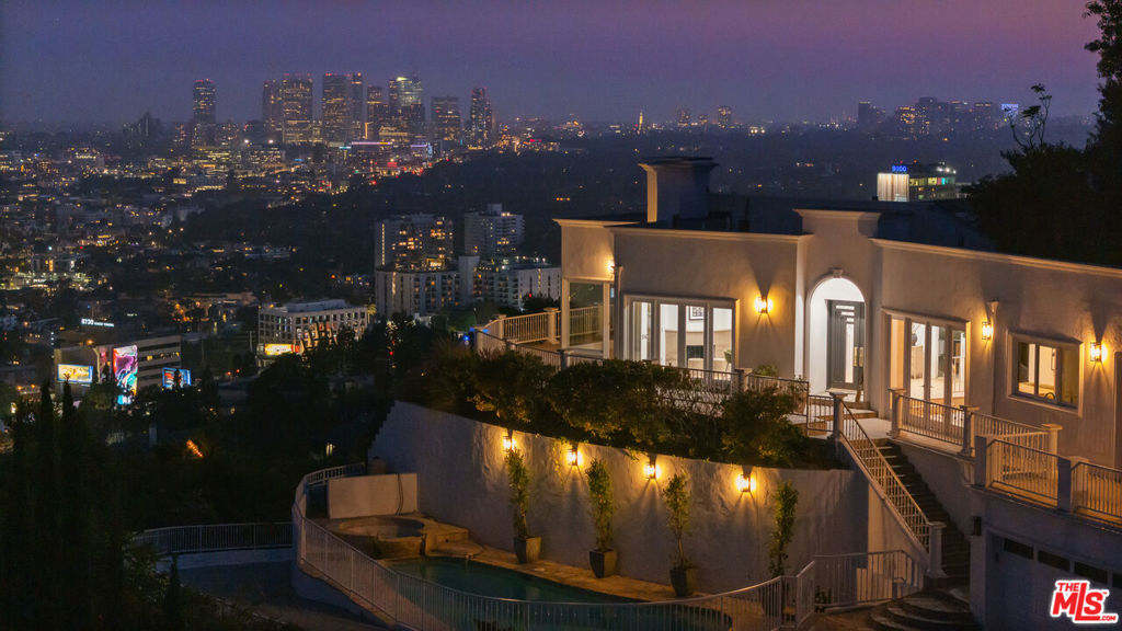 Presenting a remarkable opportunity to own a spectacular view estate perched above the famed Sunset Strip with incredible 270-degree views, among the very best in LA, that stretch from downtown to the Pacific. Move in today and refresh over time or fully redevelop, remodel, reimagine, or build anew. The possibilities are endless in this coveted, iconic locale! Up a gated, private driveway, the property wraps around its own promontory to provide dazzling vistas from multiple vantage points, balconies, patios, and nearly every room. Enjoy the pleasure of optimal indoor/outdoor flow from the foyer, bar/salon, formal living room, dining room, and bedrooms, each opening to a vast wraparound terrace. Dine-al fresco, entertain under the stars, or lounge poolside amidst striking panoramas that must be seen to be believed. The primary suite includes a bathroom with jetted tub, separate glass shower, and dual-sink vanity, giving way to a bonus living area, gym, or dance studio with skylights and fireplace. The kitchen is replete with custom cabinetry and cooktop with hood. A nearby breakfast room connects to the guest wing which was previously a separate structure and has been adjoined to the main house to create a shared lounge with patio access. The guest house offers its own separate patio, fireplace, wet bar, dining area, and kitchen, perfect for an end-user who wants to refresh and/or utilize the space for ADU income potential or short-term vacation rentals (buyer to verify local requirements). Welcome to an incredible location just moments to the area's very best shopping, fine dining, entertainment, nightlife, and so much more.