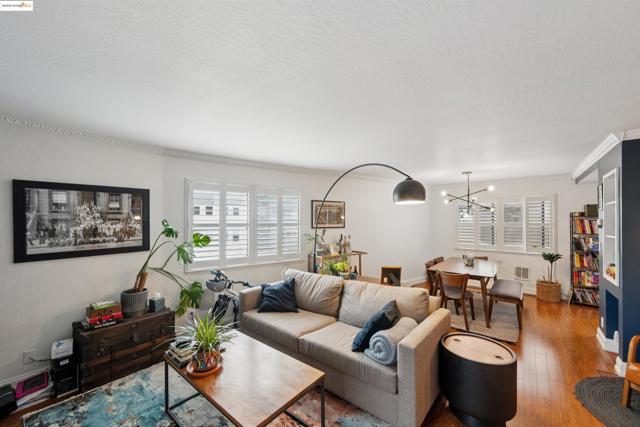 Living room with wood finished floors, plenty of natural light, a chandelier, crown molding, and a textured ceiling